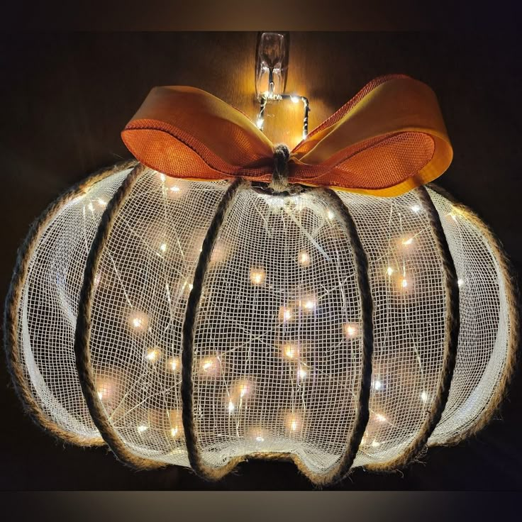 a lighted pumpkin with an orange bow on it