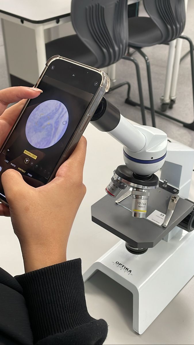 a person holding a cell phone in their hand and looking at the screen with a microscope attached to it