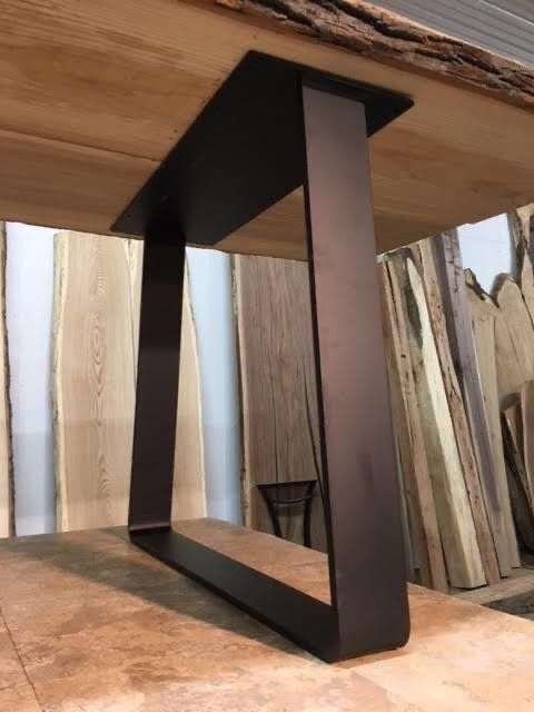 a close up of a wooden table with metal legs and wood planks in the background