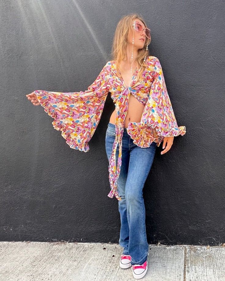 Feel like free spirited hippie queen every day in this versatile floral wrap top. Featuring a vibrant floral pattern, this beautiful top is perfect for all occasions. This top can be worn open, tied in the front, or wrapped and tied in the back making it as versatile as it is fabulous! The wide bell sleeves are reminiscent of 70s style, with a ruffled hem added for flair. The buttery soft and lightweight fabrication is guaranteed to make you feel as good as you look. Whether you wear this top to Fitted Retro Print 70s Inspired Tops, 70’s Fashion Hippie, 70s Inspired Retro Print Long Sleeve Tops, Fitted Retro Print Groovy Top, Bell Sleeve Top 70s, 1970s Retro Print Long Sleeve Tops, Floral Wrap Top, Hippie Fashion, Flared Sleeves Top