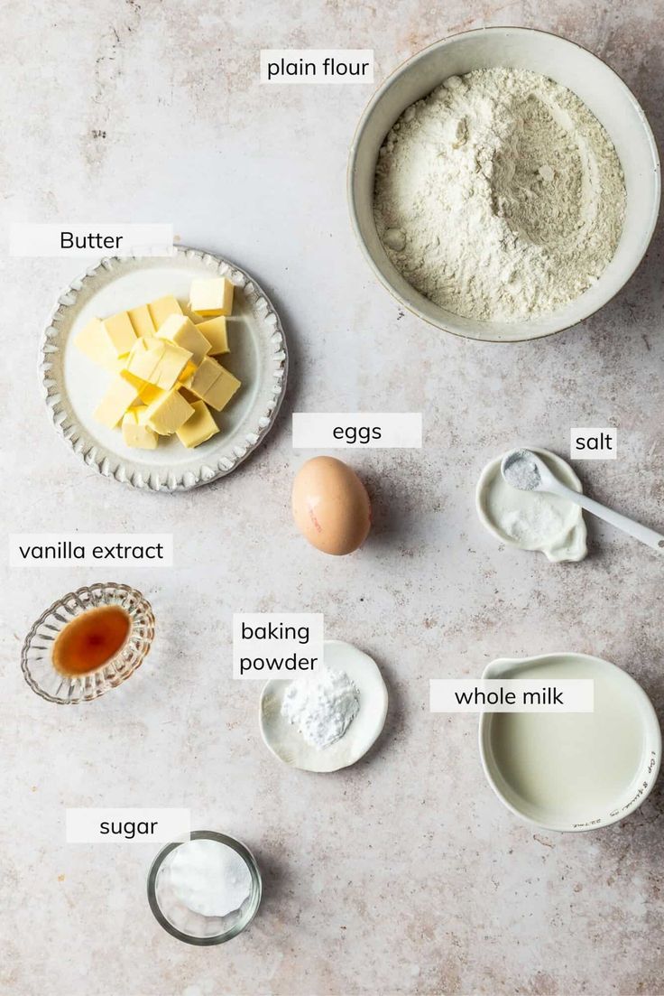 ingredients to make an egg cake laid out on a white counter top, including eggs, butter and flour