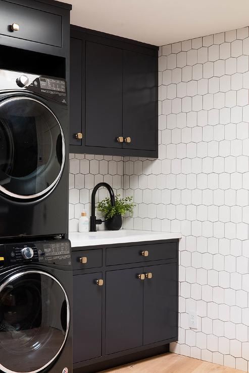 a black washer and dryer in a room with white tiles on the walls