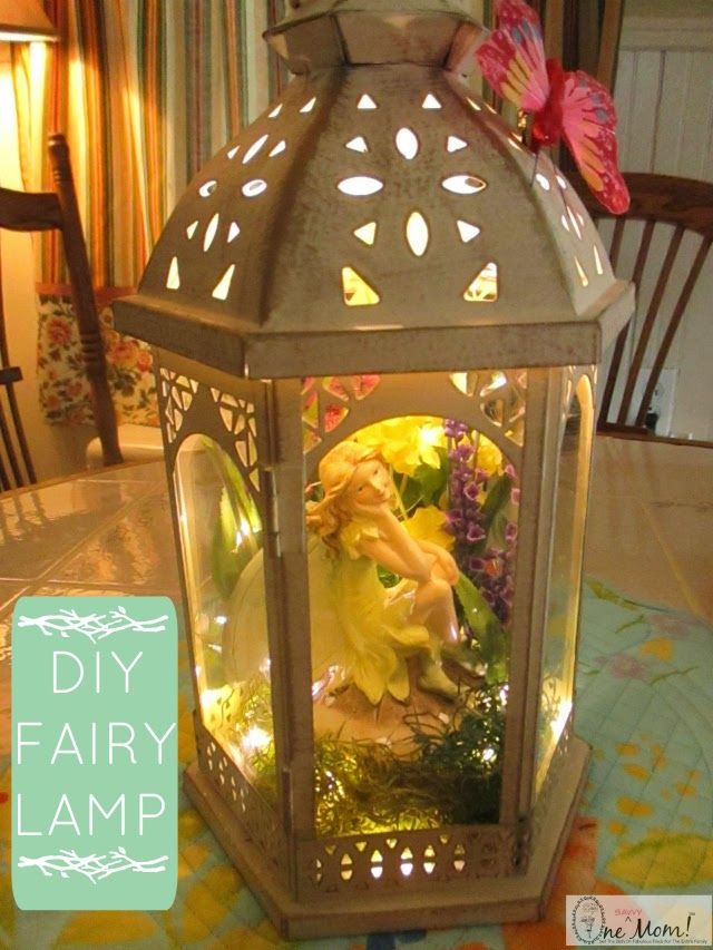 a decorative lantern with flowers inside on a dining room table and the words diy fairy lamp above it