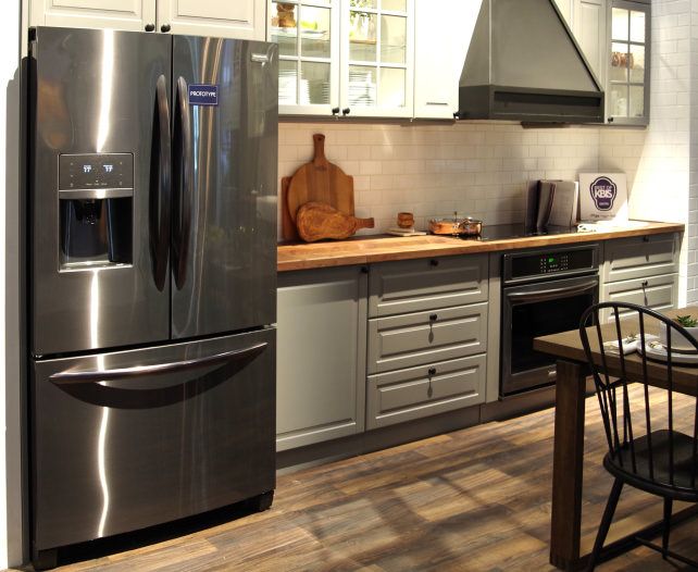 a kitchen with stainless steel appliances and wood flooring, along with white cabinetry