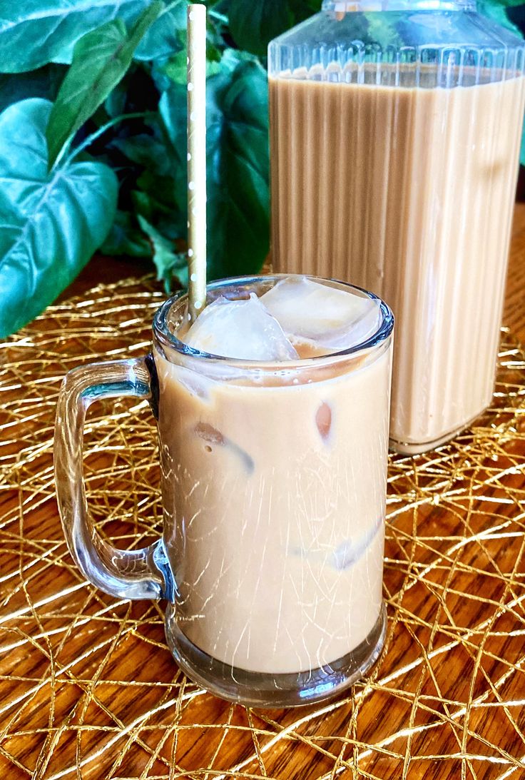 two drinks sitting on top of a wooden table next to each other with straws