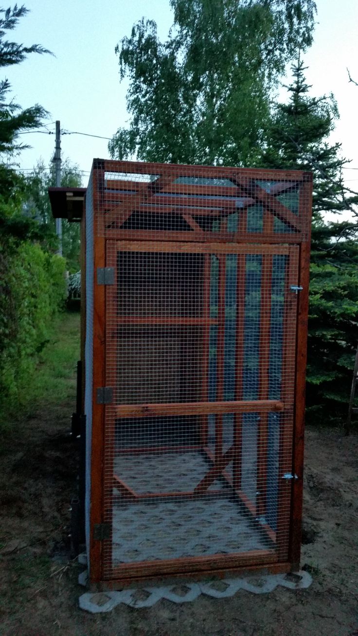 a large bird cage sitting in the middle of a field