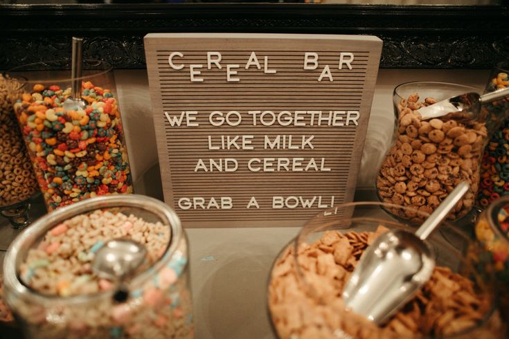 there is a sign that says cereal bar on the counter next to other food items