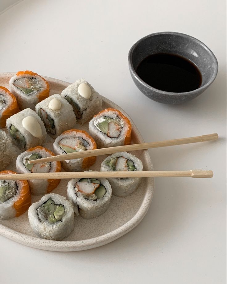 sushi on a plate with chopsticks next to it and a cup of coffee