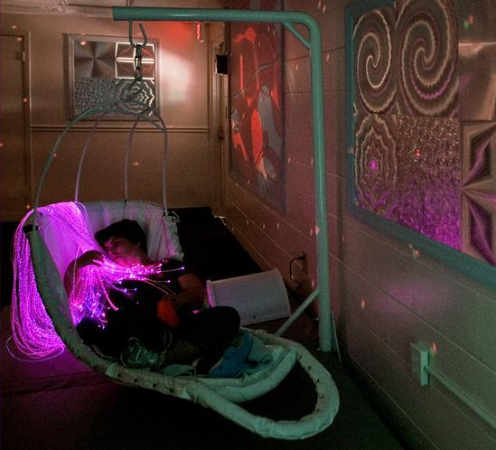 a child is sitting in a swing chair with purple lights on the wall behind them