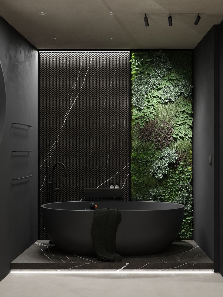 a black bath tub sitting next to a wall covered in green plants and greenery