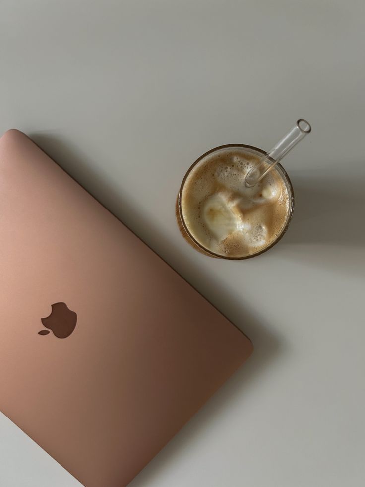 an apple laptop with a cup of coffee next to it