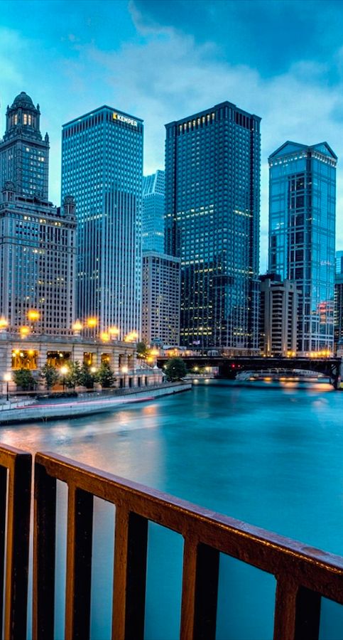 the city skyline is lit up at night, with skyscrapers in the background and water below