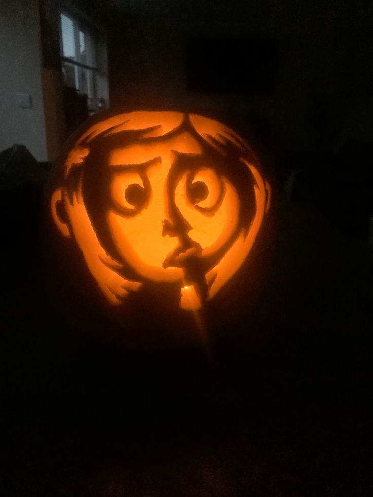 a pumpkin carved to look like a girl with eyes and nose is lit up in the dark