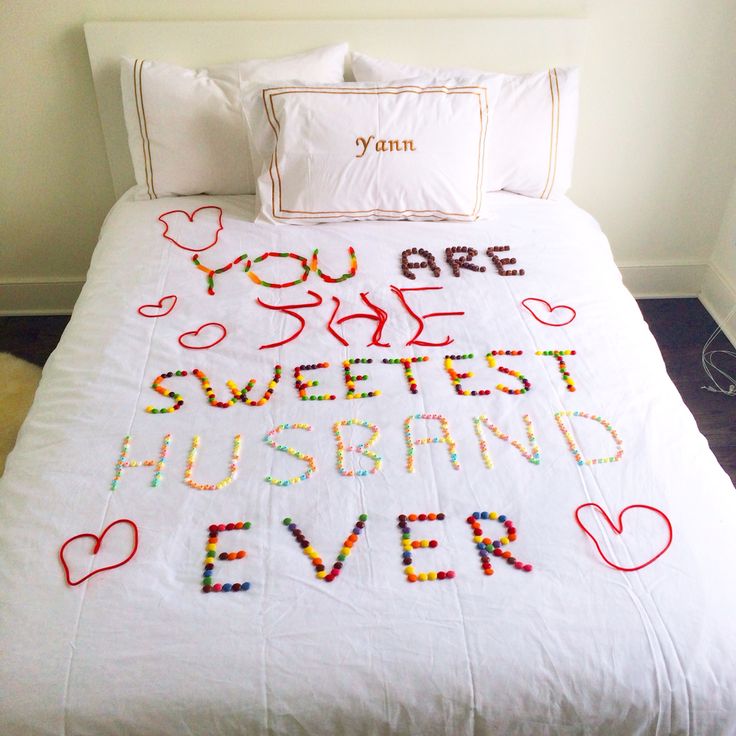 a bed with a white comforter covered in lots of colorful beads and words on it