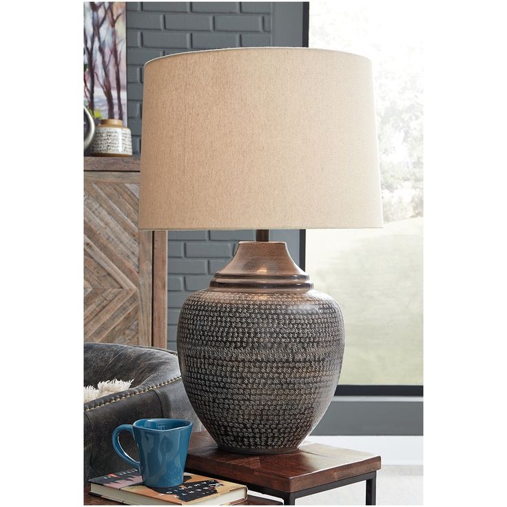 a table lamp sitting on top of a wooden table next to a couch in a living room