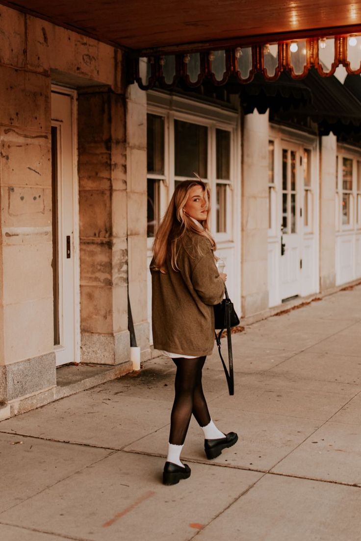 a woman is walking down the sidewalk with an umbrella in her hand and wearing black tights