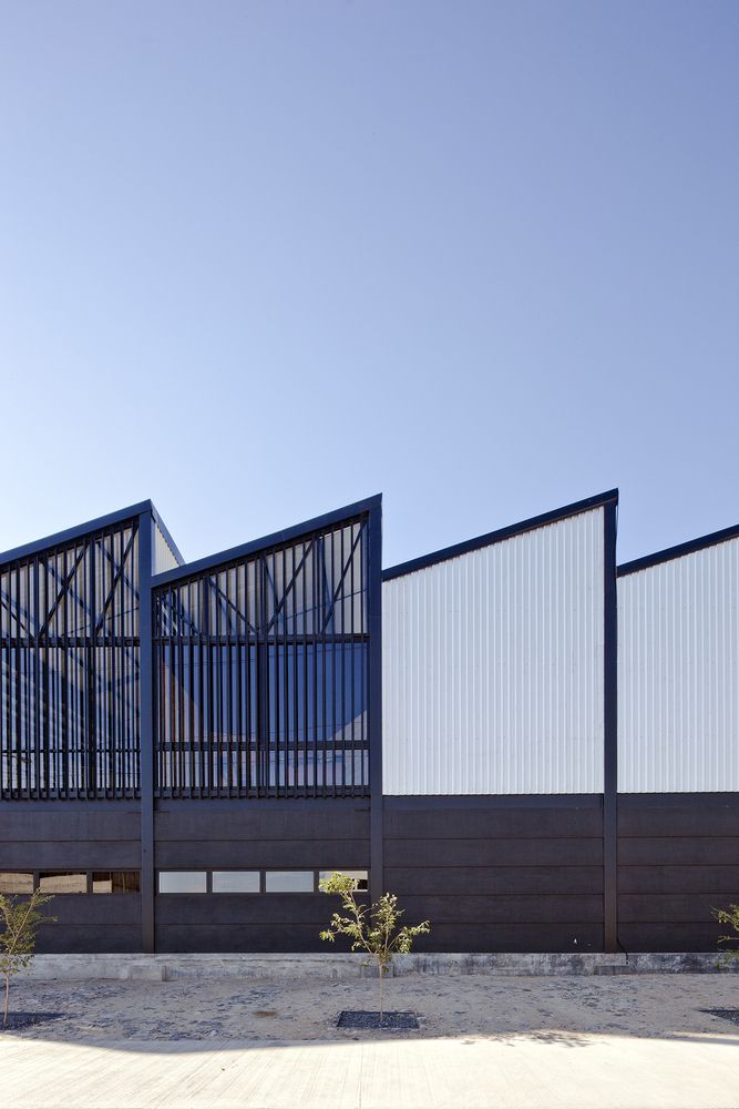 the side of a building that is made out of wood and metal with blue windows