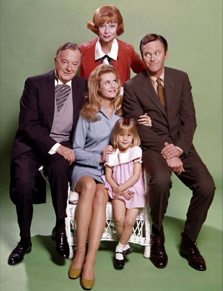 an older family poses for a portrait in front of a green background wearing suits and ties