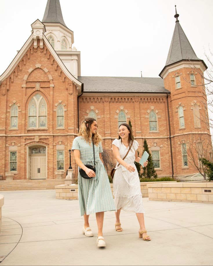 two women walking in front of a large building with steeples on it's sides