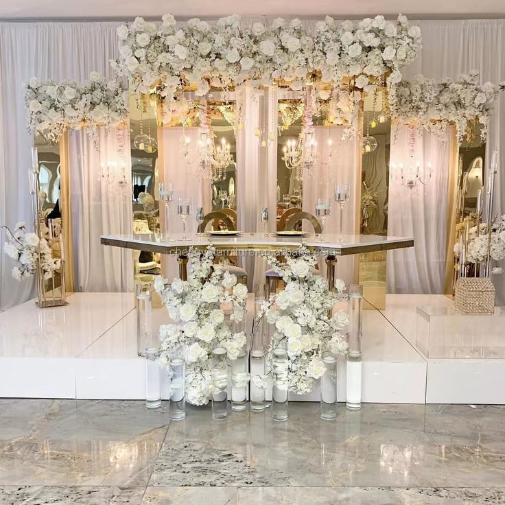 a table with flowers and candles on it in front of a white curtained room