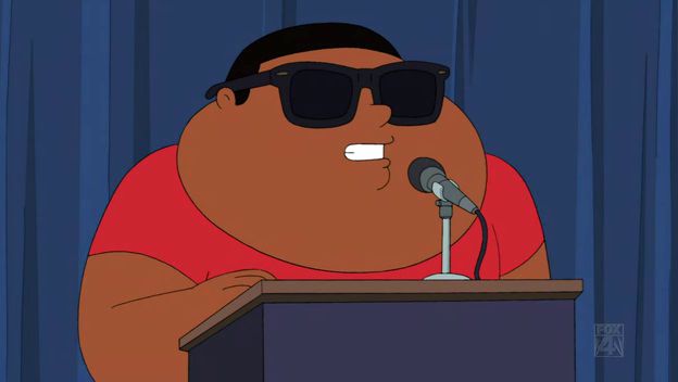 an animated man wearing sunglasses speaking at a podium with a microphone in front of him