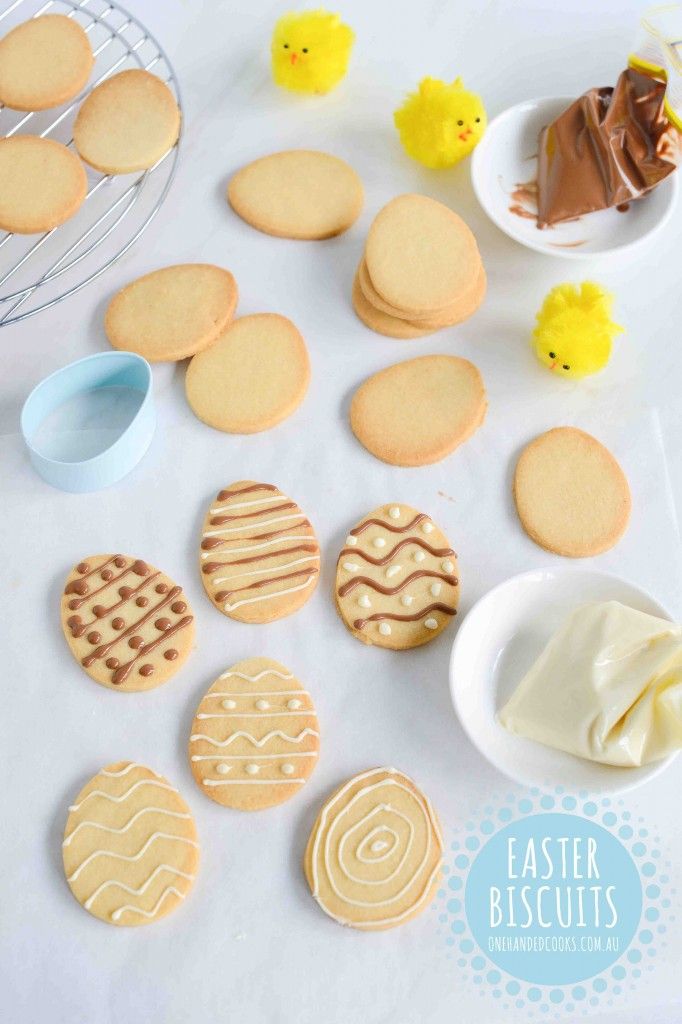 some cookies and icing on a white table with rubber ducky toys in the background