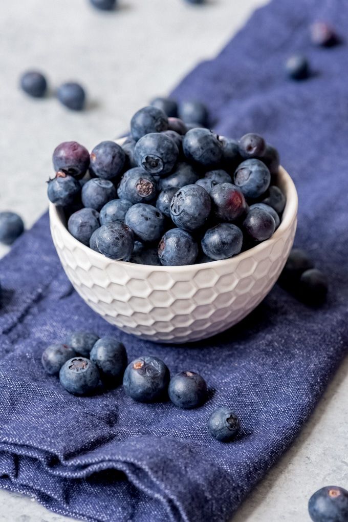 a white bowl filled with blueberries on top of a table