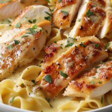 chicken and pasta with parmesan cheese in a white bowl