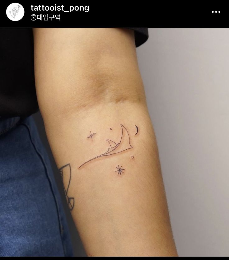 a woman's arm with a tattoo on it that has a boat and stars