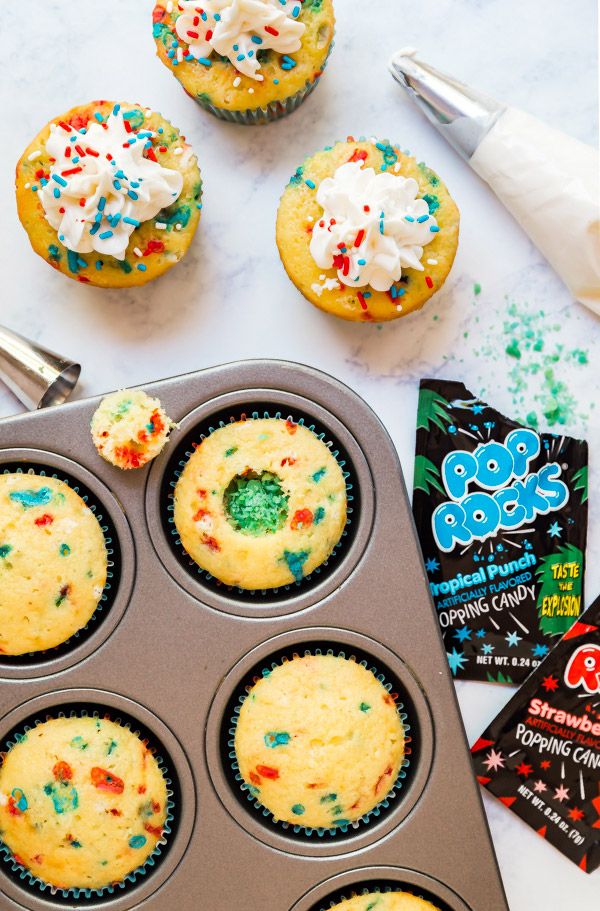 cupcakes with sprinkles and white frosting in a muffin tin