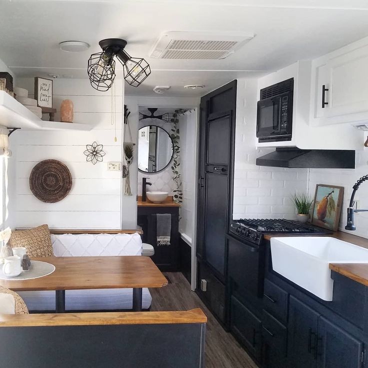 a kitchen with black cabinets, white walls and wood flooring is seen in this image