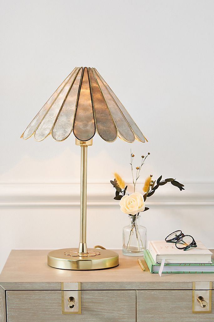 a lamp sitting on top of a dresser next to a vase with flowers in it