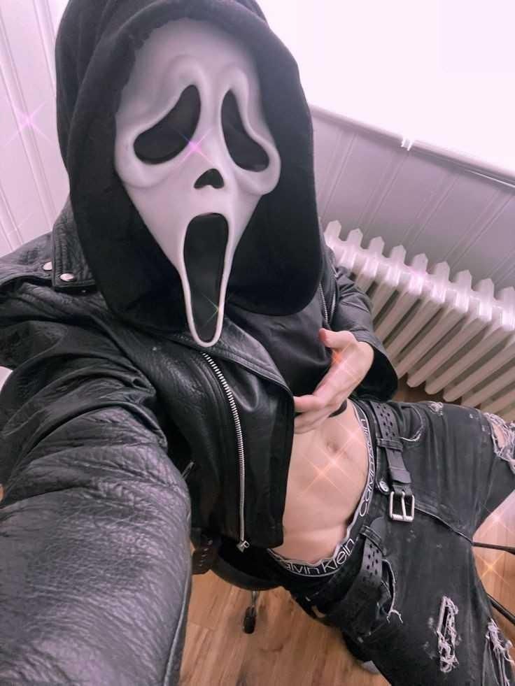 a person wearing a black hoodie with a white mask on