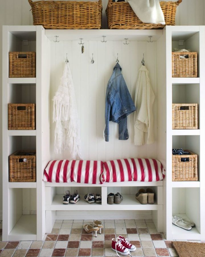 a white bench with red and white striped cushion on it next to shelves filled with shoes