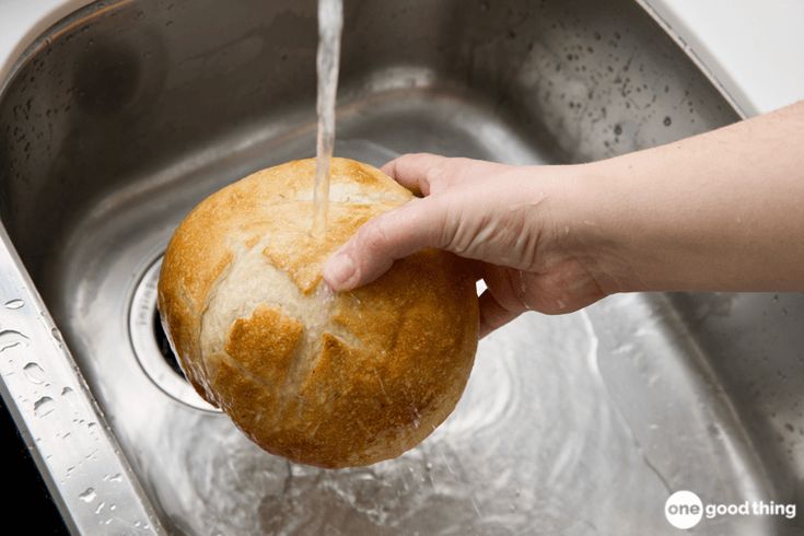 a person washing a loaf of bread in a sink