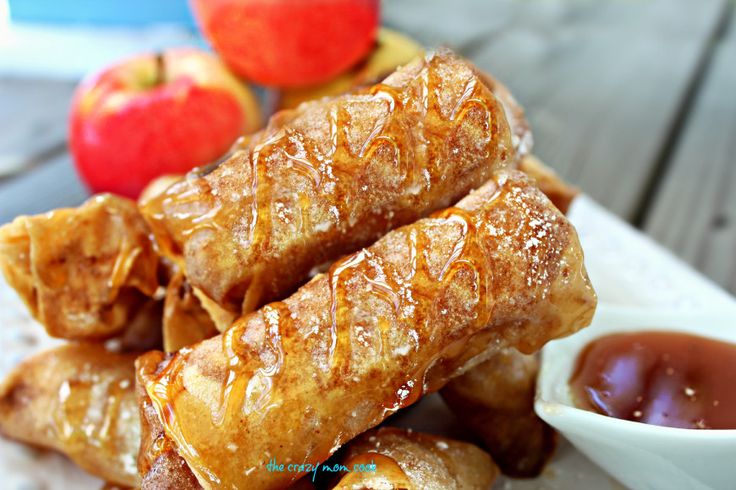 some food is on a white plate with sauce and apples in the backround