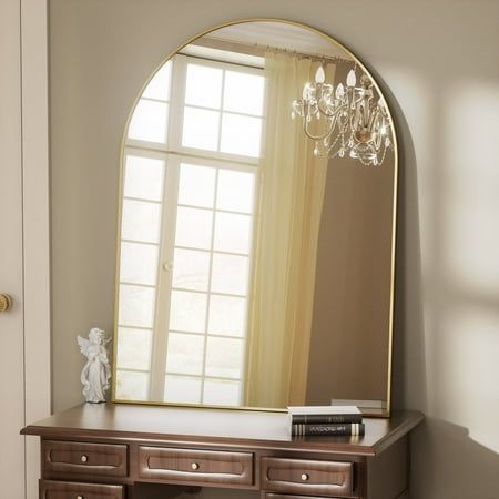 a large mirror sitting on top of a wooden dresser next to a window with a chandelier hanging from it