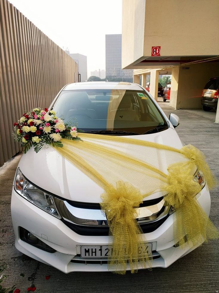 a white car decorated with yellow ribbon and flowers