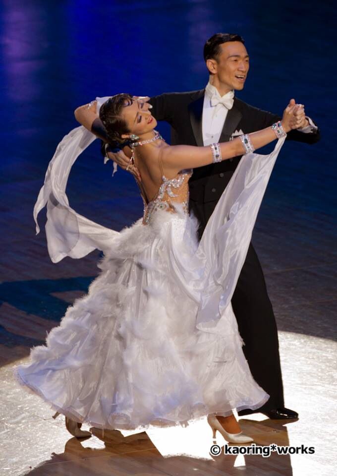 two people dressed in formal wear dancing on stage