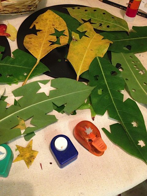 some leaves are laying on a table with glue and other crafting supplies around them