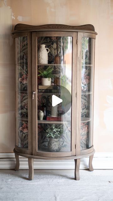 a corner cabinet with glass doors and shelves