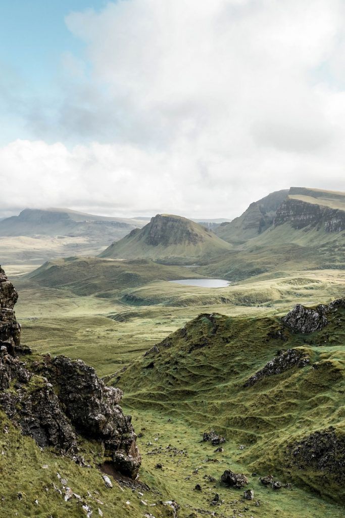 the mountains are covered in green grass and rock, with a lake on one side