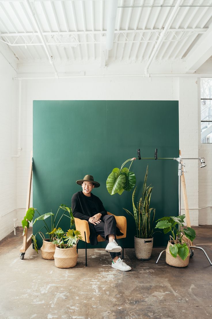 a man sitting in a chair surrounded by potted plants and houseplants on the floor