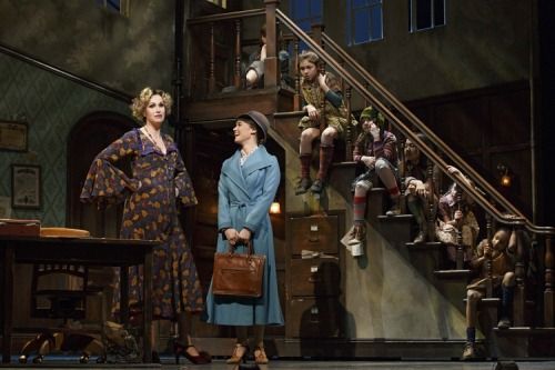 two women standing in front of a set of stairs with dolls on the steps behind them