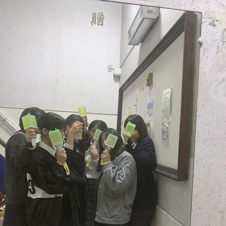 a group of young women standing next to each other in front of a mirror with sticky notes on their heads