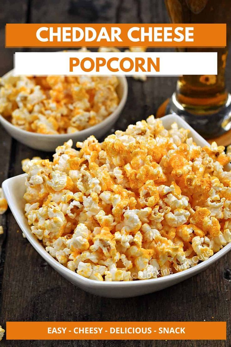 two white bowls filled with cheddar cheese popcorn on top of a wooden table