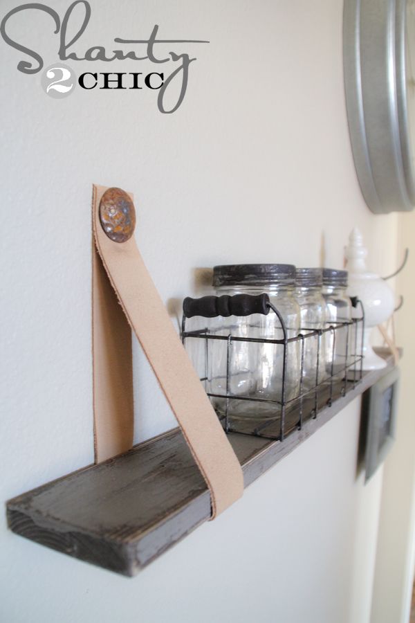 mason jars are lined up on a shelf with a leather strap hanging from the wall