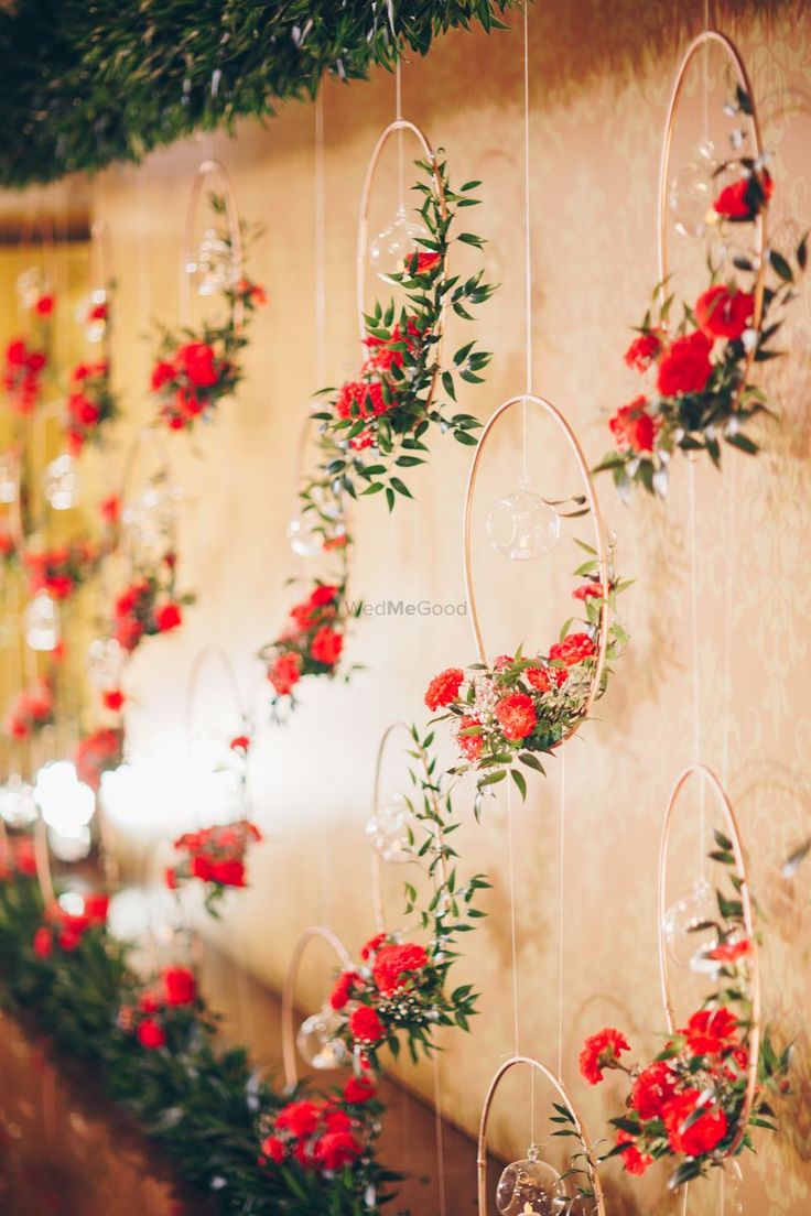 red flowers and greenery are hanging from the wall