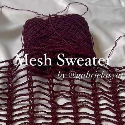 a ball of yarn sitting on top of a white sheet with the words mesh sweater written across it