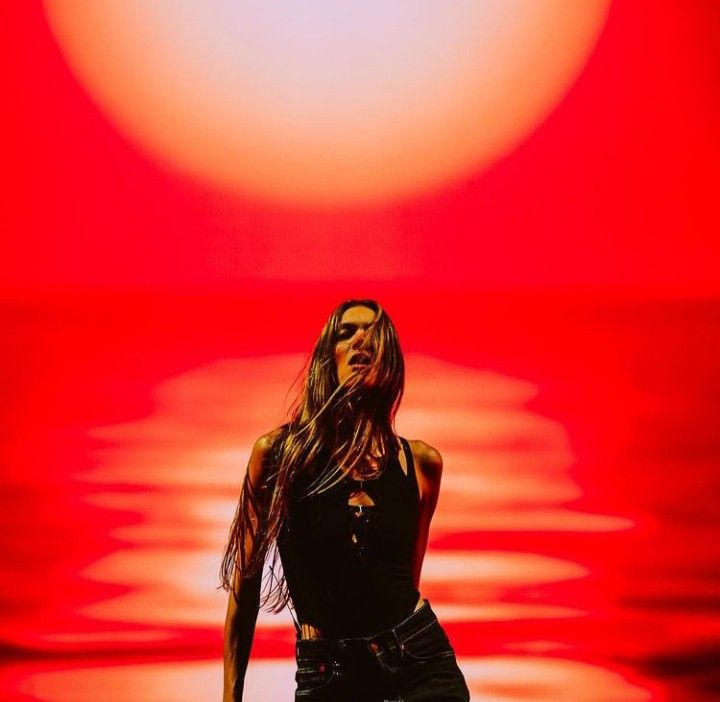 a woman with long hair standing in front of a red background